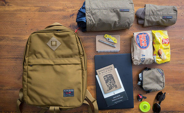 Guide's Edition Paragon in Coyote with various items around it: a sub sandwich, chips, two books, a Pinebook Pro laptop.